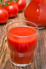 glass of tomato juice and fresh tomatoes on wooden background