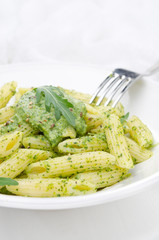pasta penne with sauce of arugula and green peas on the plate