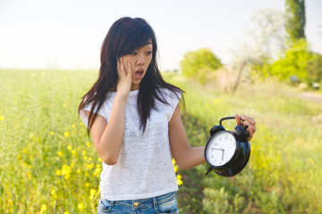 Surprised Asian Girl watching at big alarm clock