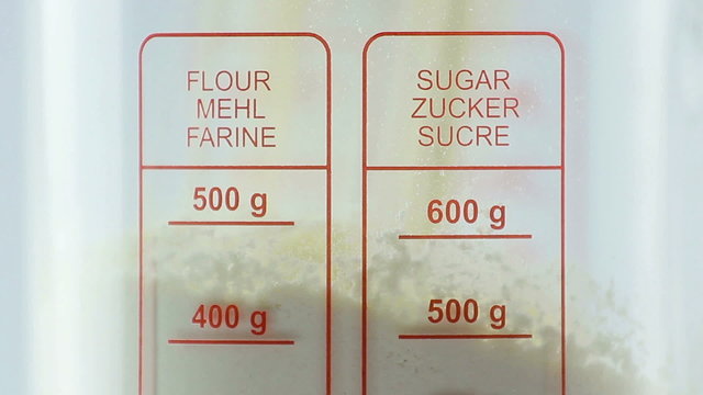 Flour beeing measured and poured into translucent glass, white i