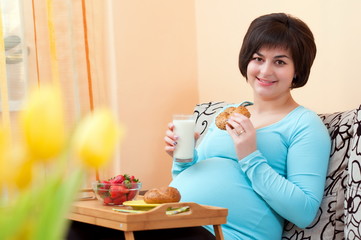 Pregnant woman eating breakfast in bed