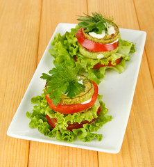 Tasty roasted marrow and tomato slices with salad leaves,