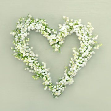 Heart shaped flower wreath on green background