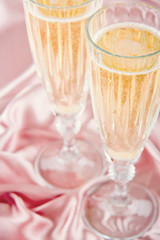 Sparkling wine on pink satin background