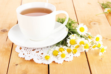 Fototapeta na wymiar Cup of chamomile tea and chamomile on wooden table