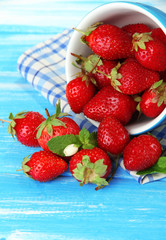 Ripe sweet strawberries in cup on blue wooden table