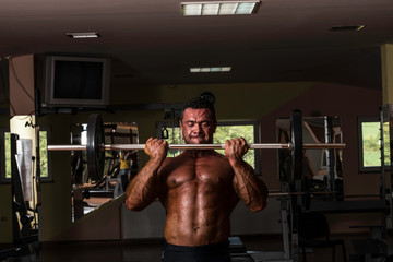 Fototapeta na wymiar bodybuilder doing heavy weight exercise for biceps with barbell