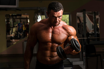 Fototapeta na wymiar bodybuilder doing heavy weight exercise for biceps with dumbbell