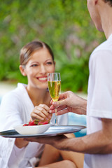 Frau am Pool bekommt Champagner