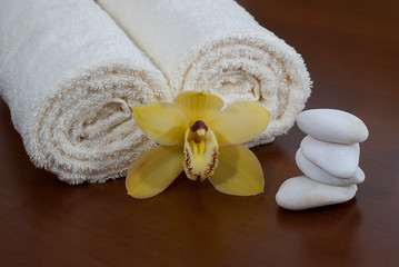 Obraz na płótnie Canvas yellow orchid with towel and massage stone