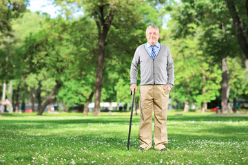 Fototapeta premium Full length portrait of a senior man walking with a cane in park