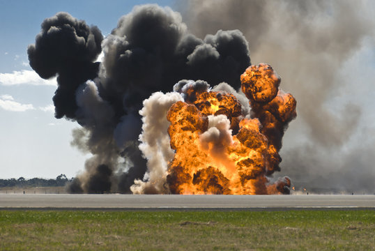 Fiery explosion with thick black smoke on an airport runway.
