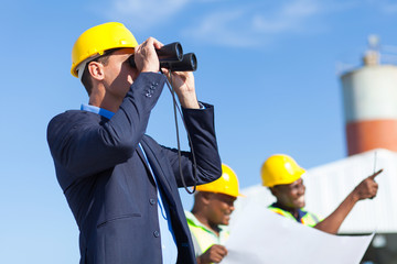 architect using binoculars looking at construction site