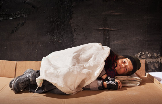 Beggar boy sleeping on cardboard sheet