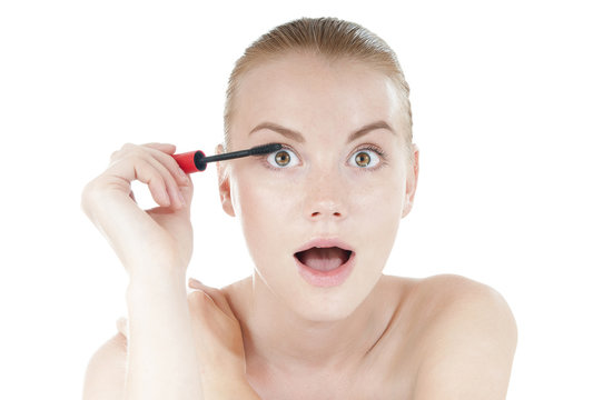 Funny  woman applying cosmetics mascara brush on white