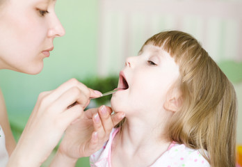mother examining little girl's throat