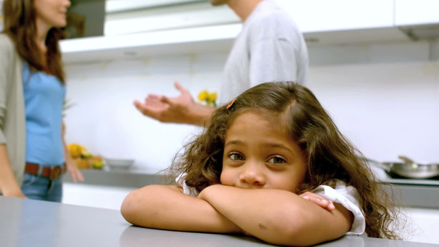 Sad girl with arms folded while parents quarreling