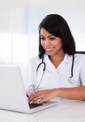 Happy Female Doctor Using Laptop