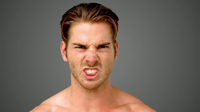 Young man showing his anger on grey background