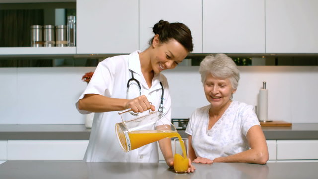 Home nurse pouring juice for patient in kitchen