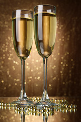 Two glasses of champagne on bright background with lights