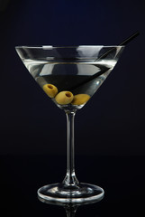Martini glass with olives on dark blue background