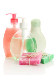 Cosmetics bottles and natural handmade soap on green background