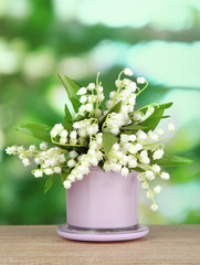 Beautiful lily of the valley in vase on nature background