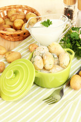 Tender young potatoes with sour cream and herbs in pan
