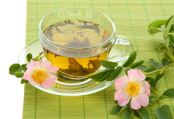 Cup of herbal tea with hip rose flowers, isolated on white