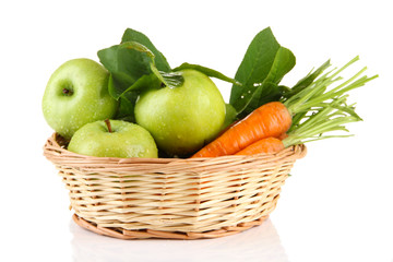 Juicy green apples and carrots with leaves in basket, isolated
