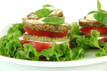 Tasty roasted marrow and tomato slices with salad leaves,