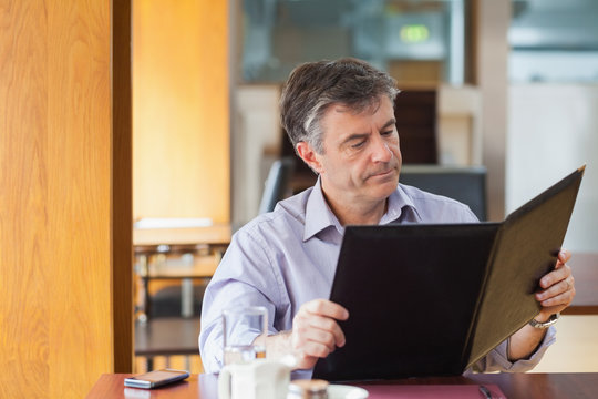 Man In A Coffee Shop Looking At The Menu