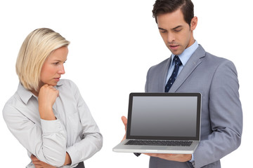 Businesswoman looking at laptop held by her colleague