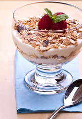 yogurt with muesli and raspberries in small glass 