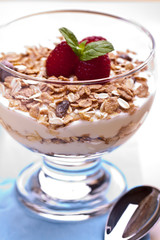 yogurt with muesli and raspberries in small glass 