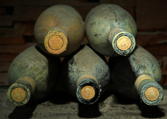 Old bottles of wine in old cellar, on dark  background