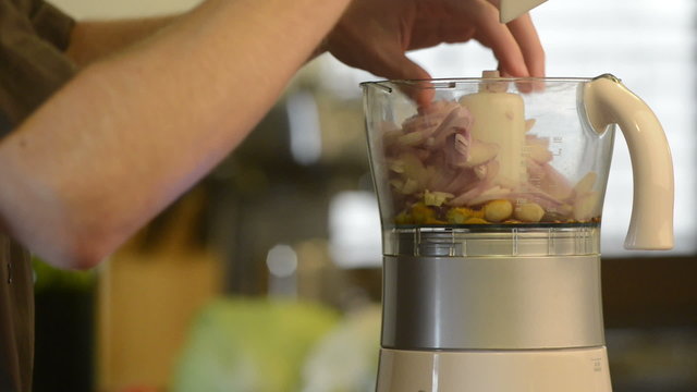 Young man blending Asian style meal ingredients in a food processor