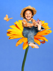 Child sitting on a huge flower playing with butterflies laughing