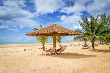 Tropical beach scenery with parasol and deck chairs in Thailand