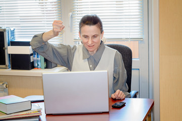 A fifty years old woman very angry with the modern technology is raging against the computer in office