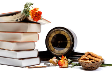 A stack of books, antique watches and cookies on a white backgro