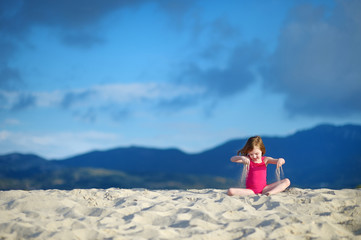 Naklejka na ściany i meble Adorable little girl playing on a sandy beach