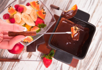 Chocolate fondue with fresh fruits on wood