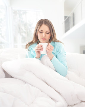 A young and attractive woman drinking coffee in the bed