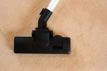Head of a modern vacuum cleaner on a beige carpet