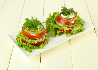 Tasty roasted marrow and tomato slices with salad leaves,