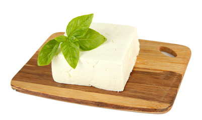 Sheep milk cheese with basil on cutting board, isolated on