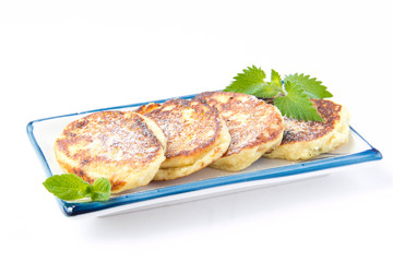 Delicious sweet cheese cakes with raisins and mint on plate on w