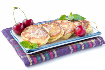 Tasty sweet cheese cakes with raisins, cherries and mint on plat